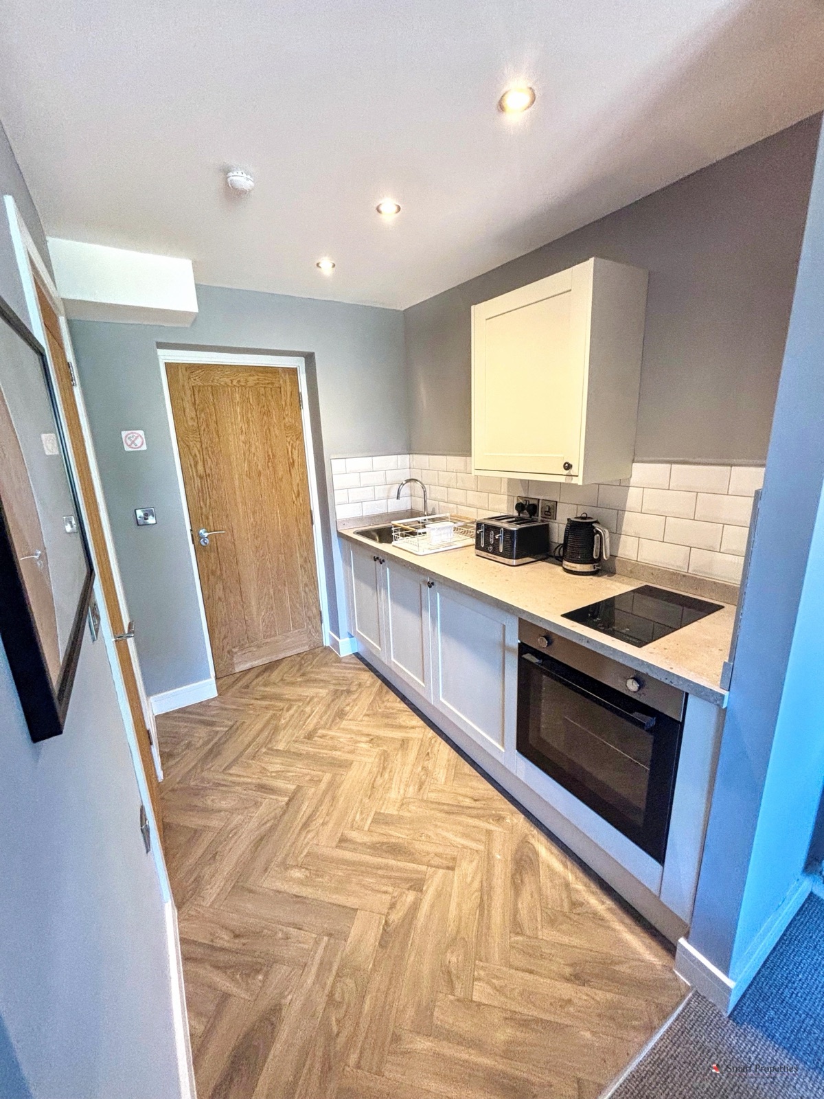 Fitted kitchen with herringbone flooring and white metro tiles