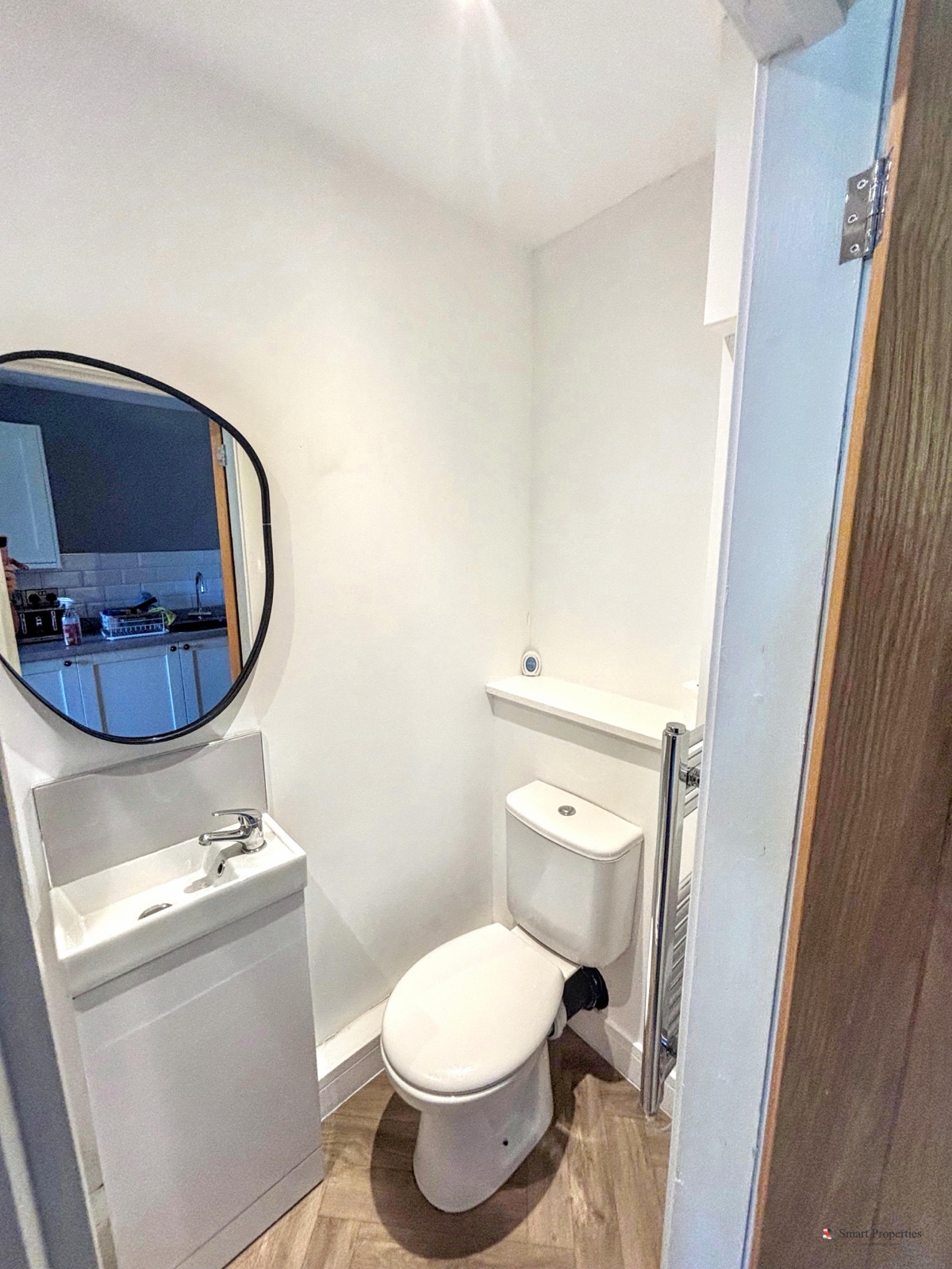 Shower room with a round mirror, white vanity unit and herringbone flooring